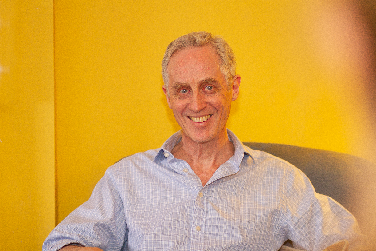 Man sitting in chair facing camera and smiliing