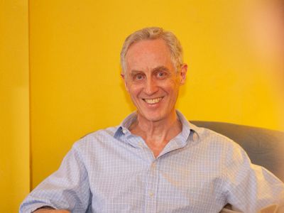 Man sitting in chair facing camera and smiliing