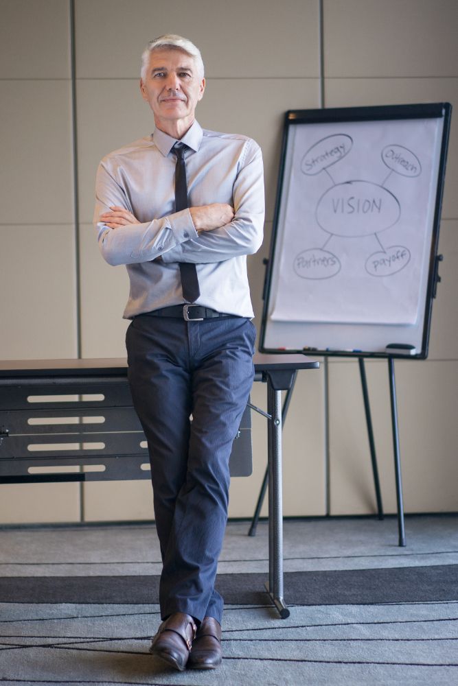 Senior lecturer with arms crossed and flipchart