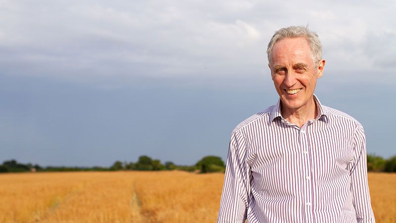 John Snowden wearing a striped shirt and standing in a field